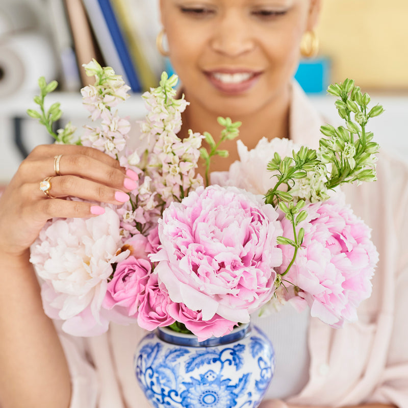 Chinoiserie artist Diane Hill holding a pretty china vase bursting with peonies and pretty pink flowers