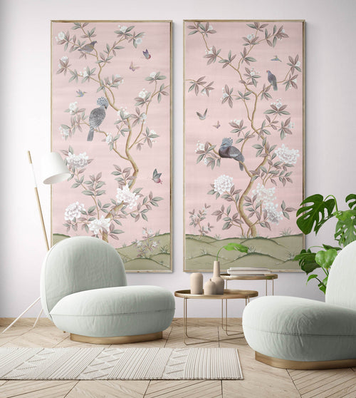 2 framed pink chinoiserie wall art panels with botanical illustrations featuring birds, butterflies, and flowers hung on wall