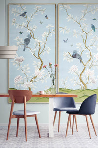 pair of 2 framed blue chinoiserie wall panel prints with botanical illustrations featuring birds, butterflies, and flowers hung on wall