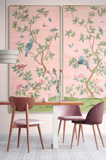 pair of two framed pink and green chinoiserie wall art panel with botanical illustrations featuring birds, butterflies, and flowers hung on wall