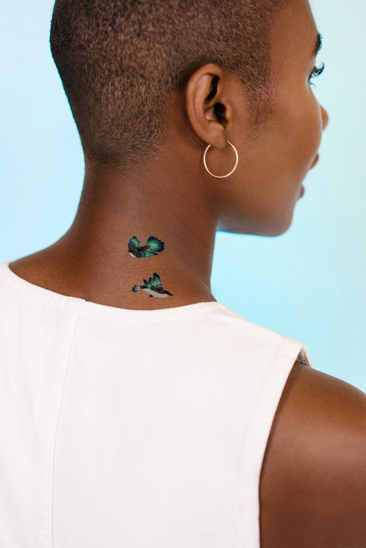 A woman shows off her neck, bearing Chinoiserie inspired temporary tattoos, design by Diane Hill in collaboration with Tattly