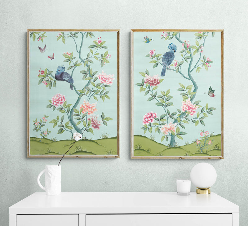 pair of 2 framed blue and green chinoiserie wall art prints with botanical illustrations featuring birds, butterflies, and flowers hung on wall