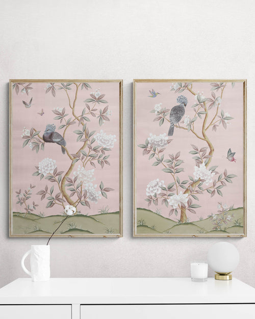 2 framed pink chinoiserie wall art prints with botanical illustrations featuring birds, butterflies, and flowers hung on wall