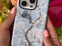 luxury chinoiserie phone case with botanical illustrations being applied to an iPhone