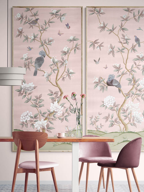 2 framed pink chinoiserie wall art panels with botanical illustrations featuring birds, butterflies, and flowers hung on wall