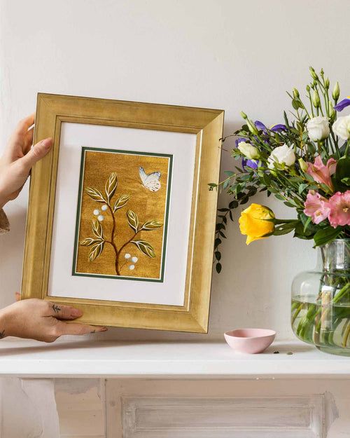framed chinoiserie wall art print featuring vintage Chinese-style butterfly and flower branch on gold background on mantle