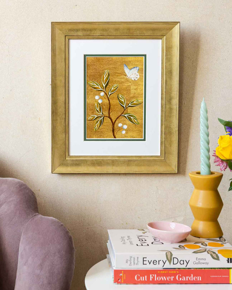 framed chinoiserie wall art print featuring vintage Chinese-style butterfly and flower branch on gold background hung on wall