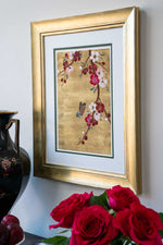 framed chinoiserie wall art print featuring Japanese-style cherry blossom branch and butterfly on gold leaf background hung on wall