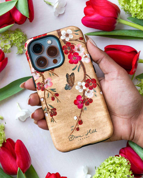 hand holding luxury chinoiserie phone case featuring a vintage inspired butterfly and cherry blossom branches on a gold background