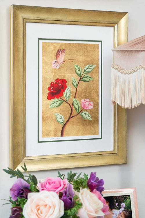 framed chinoiserie wall art print featuring vintage-style butterfly and flower branch on gold leaf background hung on wall