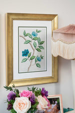 framed chinoiserie wall art print featuring blue vintage-style butterfly and flower branch on silver background hung on wall
