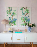 pair of framed Chinoiserie style art prints featuring butterflies and blue flowers on an ivory cream background hung on wall