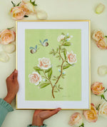 hands holding framed green botanical chinoiserie wall art print featuring vintage style flowers and butterflies