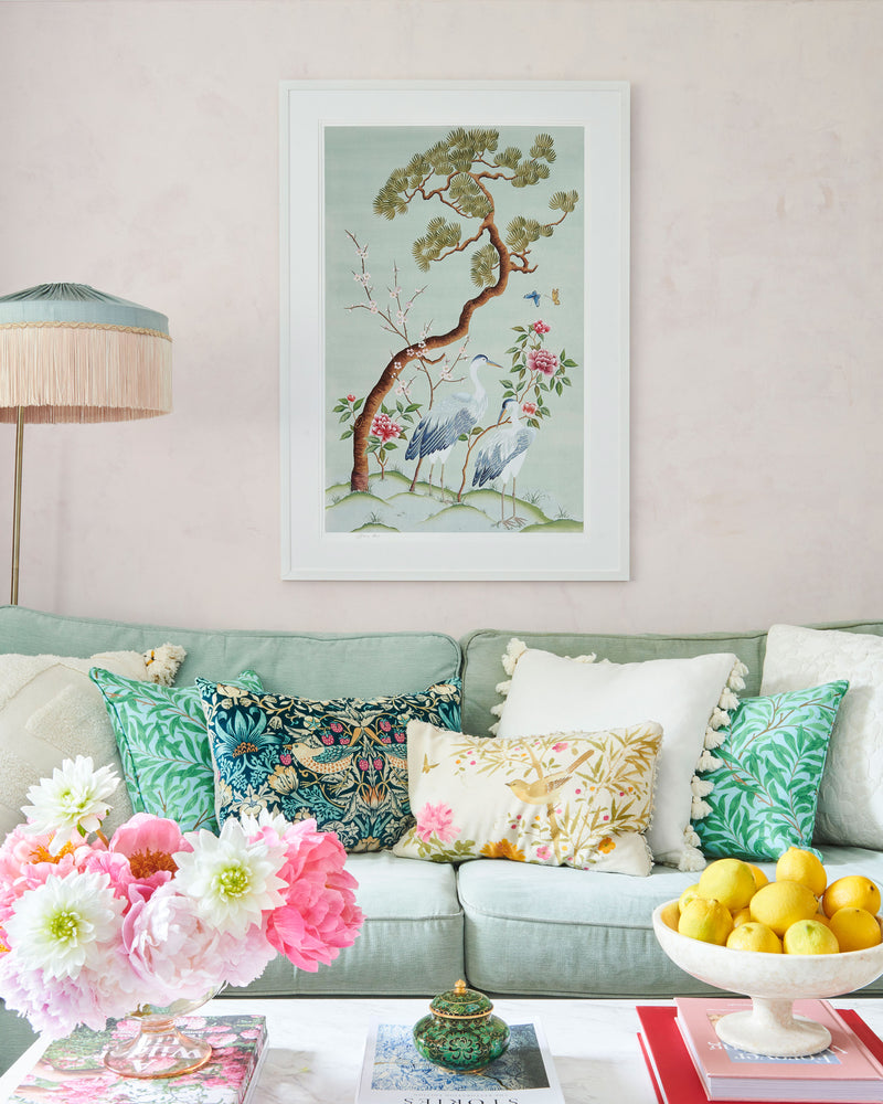 blue framed chinoiserie wall art print featuring antique inspired herons, flowers, and blossoms beneath a pine tree with butterflies hung on wall
