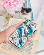hand holding blue luxury chinoiserie phone case featuring two colourful vintage inspired birds on fruit and flower branches