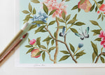 close up of blue modern chinoiserie wall art print featuring two birds, flowers, branches, and fruit on blue background
