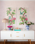 pair of framed Chinoiserie style art prints featuring butterflies and pink flowers on a pastel pink background hung on wall