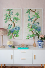 pair of two framed Chinoiserie style art prints featuring butterflies and blue flowers on an ivory cream background hung on wall