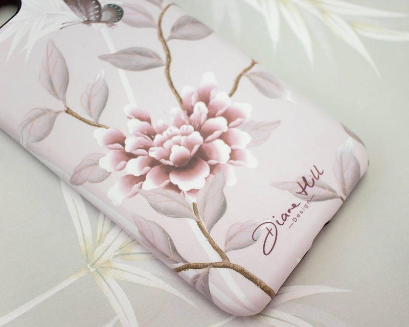 close up of pink luxury phone case featuring vintage style butterfly and flower branches with a bamboo background