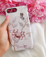 hand holding pink luxury phone case featuring vintage style butterfly and flower branches with a bamboo background