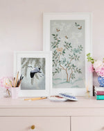 two pebble blue and silver framed chinoiserie wall art prints of various sizes featuring a bird, butterflies, flower branches, and bamboo 