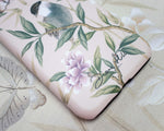 close up of pink luxury phone case featuring vintage style bird, butterfly and flower branches with a bamboo background
