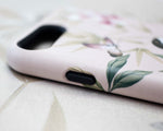 close up of pink luxury phone case featuring vintage style bird, butterfly and flower branches with a bamboo background