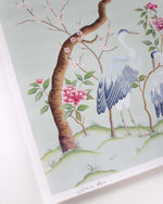 close up of blue chinoiserie wall art print featuring antique inspired herons, flowers, and blossoms beneath a pine tree with butterflies