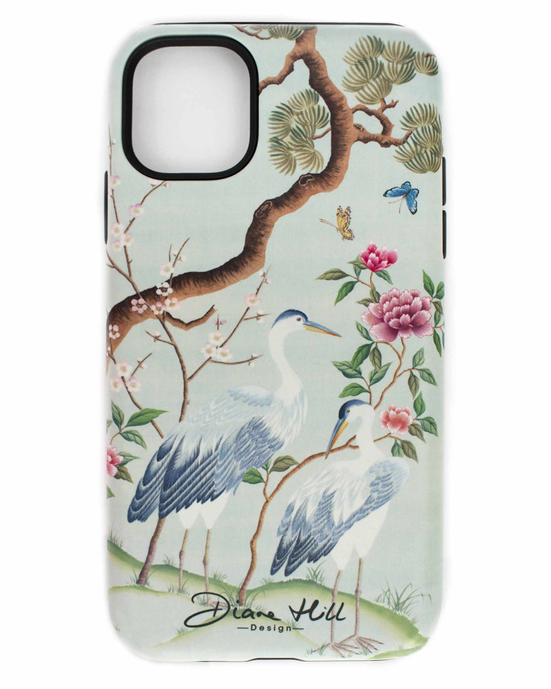 blue luxury chinoiserie phone case featuring antique inspired herons, flowers, and blossoms beneath a pine tree with butterflies