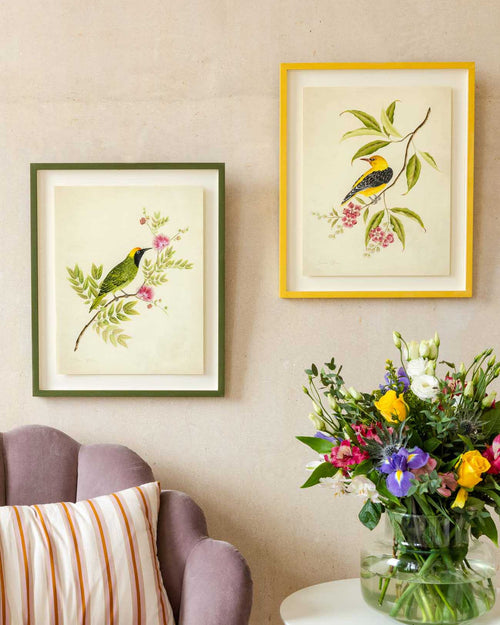 pair of two framed botanical wall art prints featuring gold sparkle embellished exotic birds on tree branches with flowers hung on wall