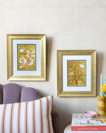 pair of framed chinoiserie wall art print featuring vintage Chinese-style butterfly and flower branch on gold background hung on wall