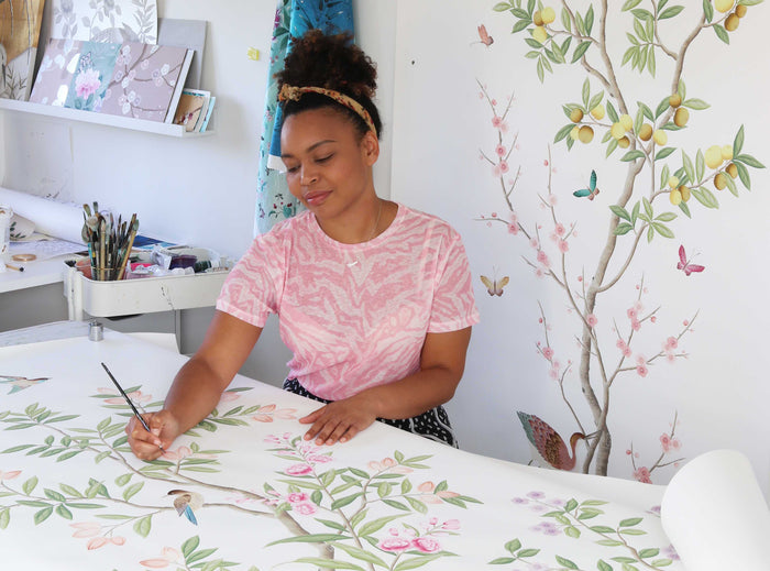 watercolour artist diane hill holding Chinese paintbrush to paint chinoiserie wallpaper design with gouache paint on silk paper