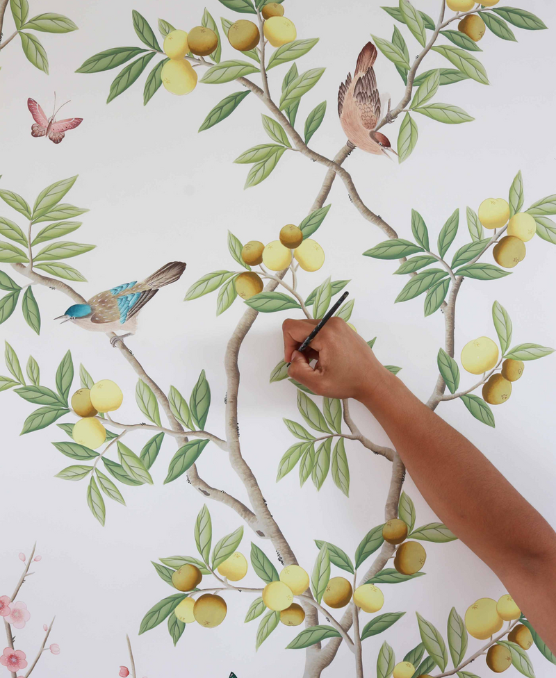 Diane Hill's handing holding a paintbrush and painting the details onto the original design for her 'Chinoiserie Chic' wallpaper in collaboration with Rebel Walls