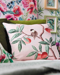 pink botanical fabric featuring chinoiserie style birds, branches, and butterflies on cushion