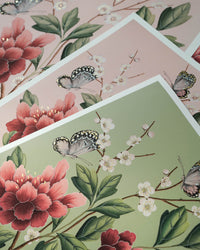 close up of pink and green chinoiserie art prints featuring butterflies and flowers with 24 carat gold embellishements