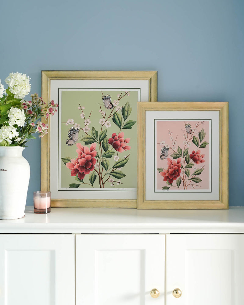 two framed pink and green chinoiserie art print featuring red flowers, cherry blossoms, and butterflies on wall