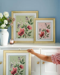 three framed pink and green chinoiserie art print featuring red flowers, cherry blossoms, and butterflies in living room set 