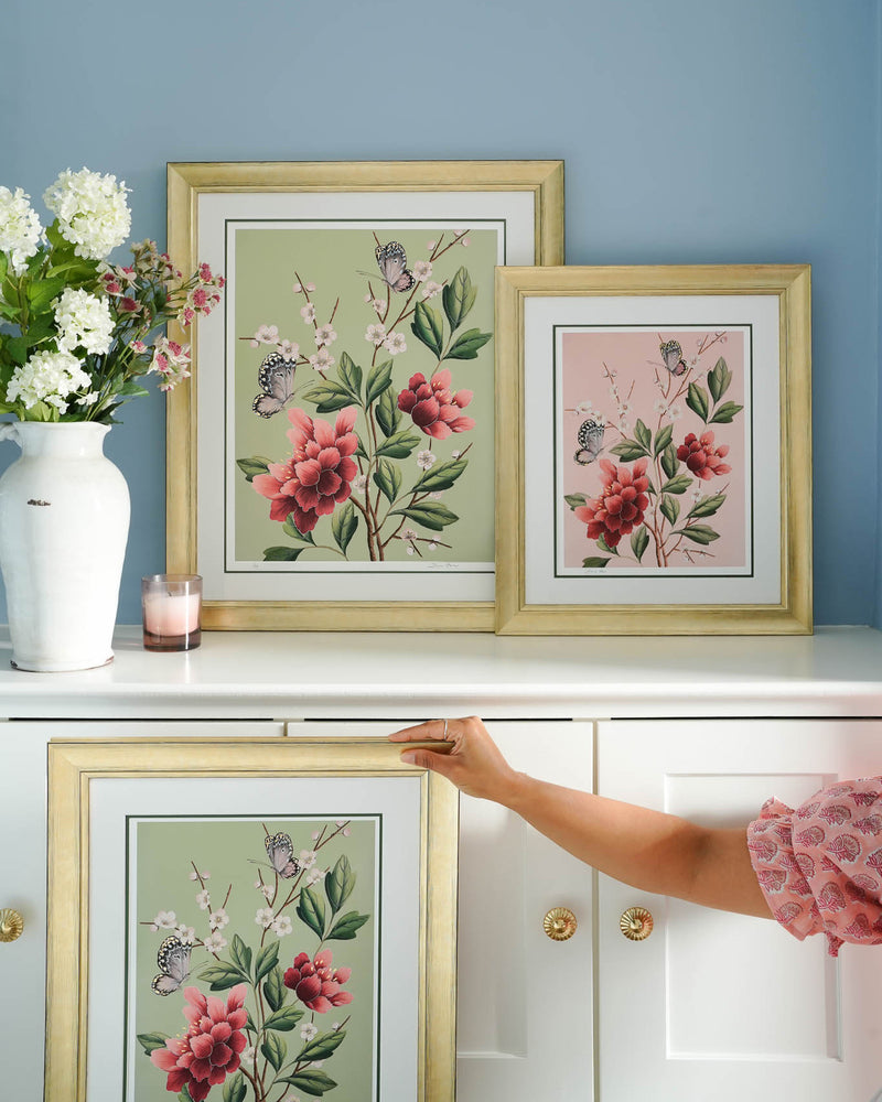 three framed pink and green chinoiserie art print featuring red flowers, cherry blossoms, and butterflies in living room set