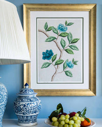 framed chinoiserie wall art print featuring blue vintage-style butterfly and flower branch on silver background hung on wall