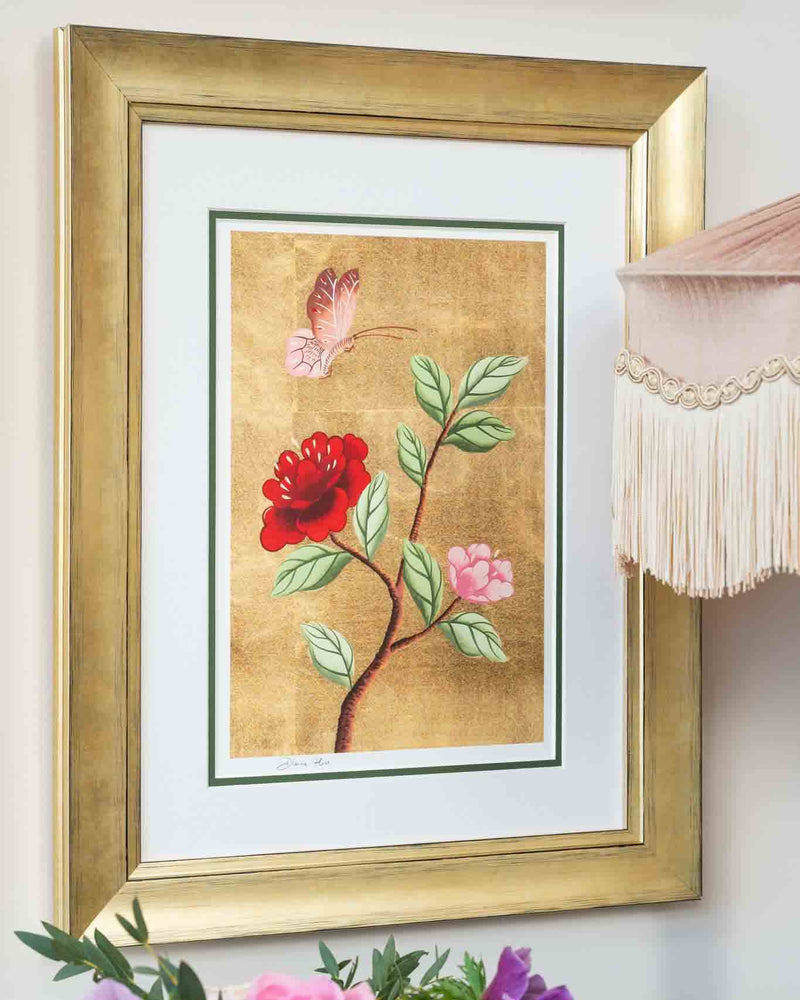 framed chinoiserie wall art print featuring vintage-style butterfly and flower branch on gold leaf background hung on wall