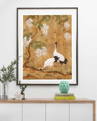 framed Japanese style chinoiserie wall art print featuring cranes and wisteria tree on gold background hung on wall