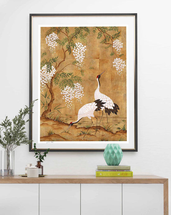 framed Japanese style chinoiserie wall art print featuring cranes and wisteria tree on gold background hung on wall