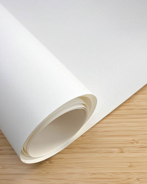 close up image of roll of white silk paper on wooden table