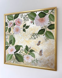 Diane Hill's original chinoiserie painting 'Mottled Lush Blooms And Butterflies (A)' in a gold frame on a plain white wall