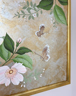 Close up corner Diane Hill's original chinoiserie painting 'Mottled Lush Blooms And Butterflies (A)' in a gold frame on a plain white wall