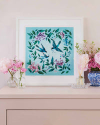 blue framed chinoiserie wall art print featuring three vintage inspired birds surrounded by leaves and flowers on set of drawers