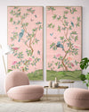 pair of two framed pink and green chinoiserie wall art panel with botanical illustrations featuring birds, butterflies, and flowers hung on wall