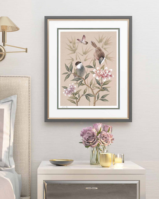 blush pink framed chinoiserie wall art print featuring vintage style birds, butterfly and flower branches with a bamboo background in bedroom above bedside table