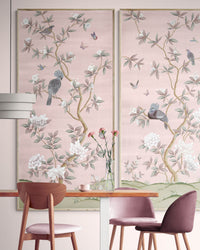 2 framed pink chinoiserie wall art panels with botanical illustrations featuring birds, butterflies, and flowers hung on wall