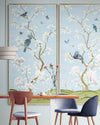 pair of 2 framed blue and white chinoiserie wall panel prints with botanical illustrations featuring birds, butterflies, and flowers hung on wall